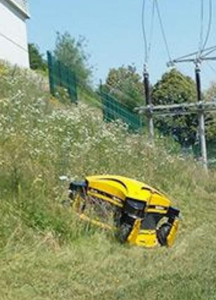 Ferngesteuerter Hangmäher vor einem Bauernhaus